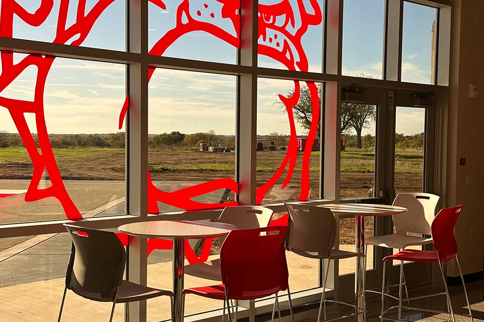 Student tables in front of a window with a large red bulldog decal