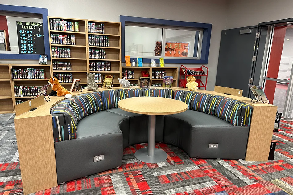 a round bookshelf with a couch on one side in a library