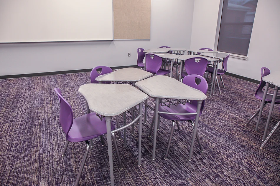A cluster of three desks with purple chairs