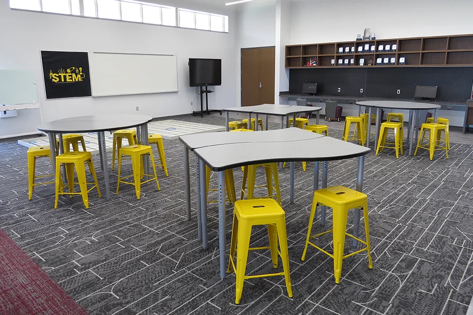 Tables with bright yellow stools in a STEM classroom