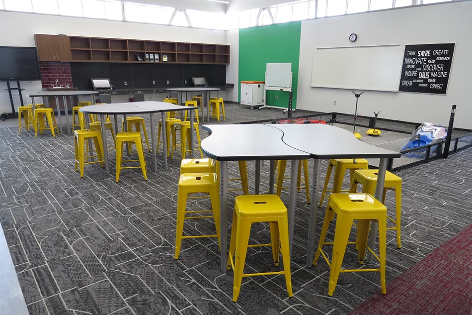 Tables with bright yellow stools in a STEM classroom