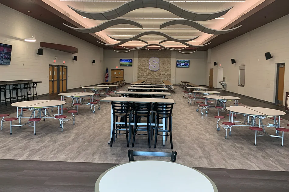 Rows of round and rectangular tables in a school lunchroom